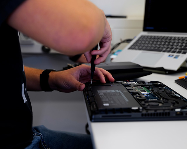 IT trainee removes the hard disk from a laptop.