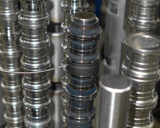 Aufbau einer Untersuchungscharge mit Türmen aus Lagerringen:​ Im Vordergrund Innenringe auf Kernstange aufgezogen mit Thermoelementzuführung in ein Messelement, im Hintergrund und rechts Außenringe​.